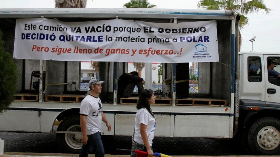 People walk past a truck of Empresas Polar during a protest in Maracaibo, in the state of Zulia, Venezuela, April 29, 2016. The placard reads "This truck is empty because the government decided to take the raw material to Polar. But still full of desire and effort!".