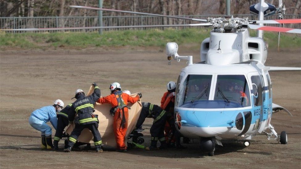 Спасатели доставляют человека без сознания из вертолета береговой охраны Японии в машину скорой помощи в Уторо в Шари, остров Хоккайдо, Япония, 24 апреля 2022 г., после того, как 23 апреля 2022 г. пропал туристический катер с 26 людьми.