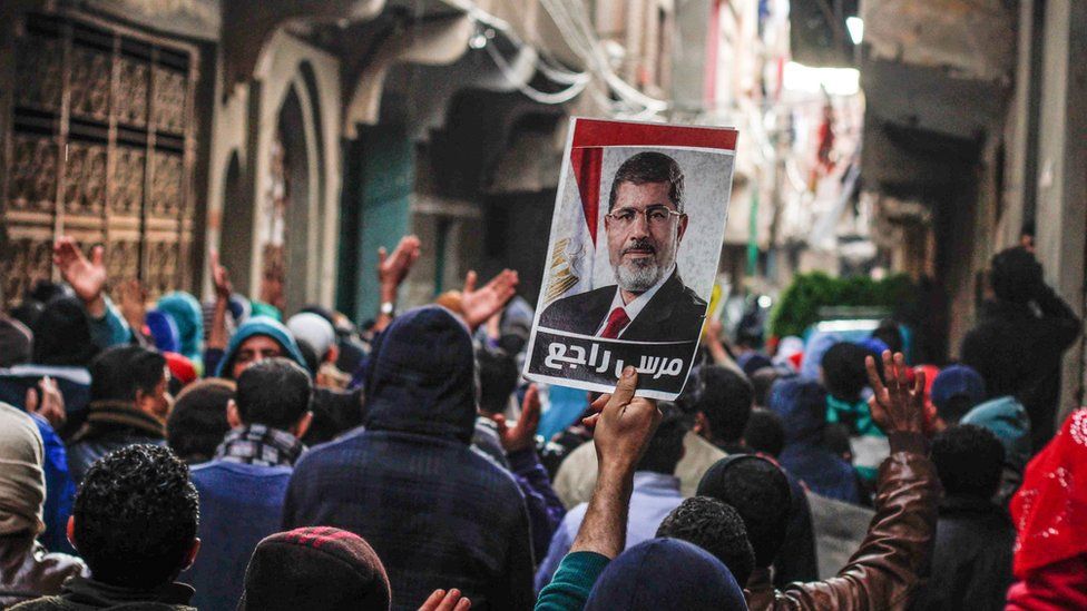 Morsi supporters hold up a photo of the ousted president on the fifth anniversary of the 2011 uprising in Cairo, Egypt (25 January 2016)