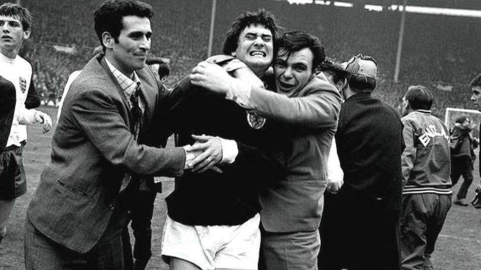 Jim Baxter being hugged on the Wembley pitch after Scotland defeated England in 1967