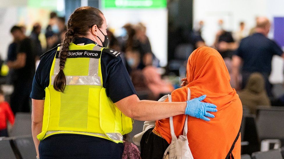 A woman from Border Force puts her hand on the back of an Afghan woman as she arrives from Afghanistan at Heathrow Airport in August 2021