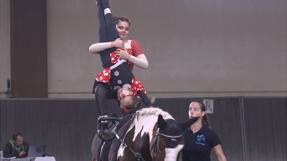 Two children riding a horse, one holding the other upside down