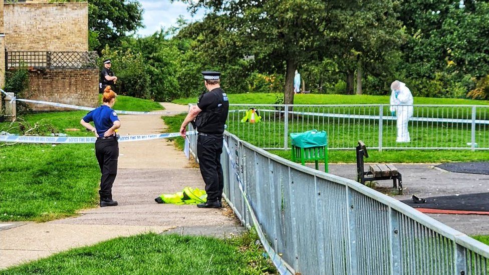 Police and forensics officers in white suits at Joyners Field, Harlow, Essex