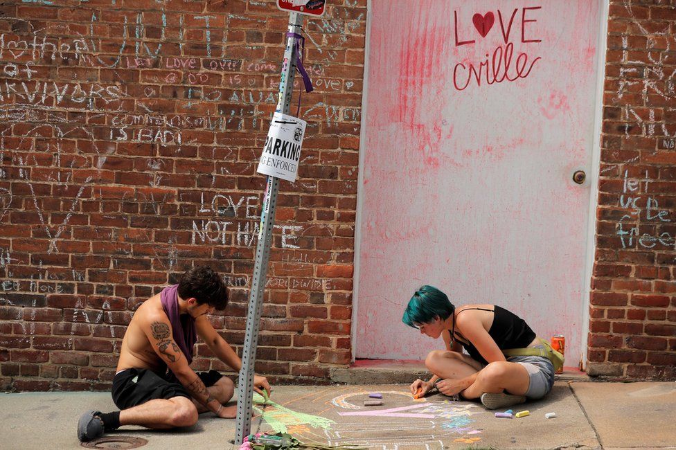 People draw on a sidewalk near a memorial to Heather Heyer ahead of the one year anniversary of the 2017 Charlottesville "Unite the Right" protests in Charlottesville, Virginia