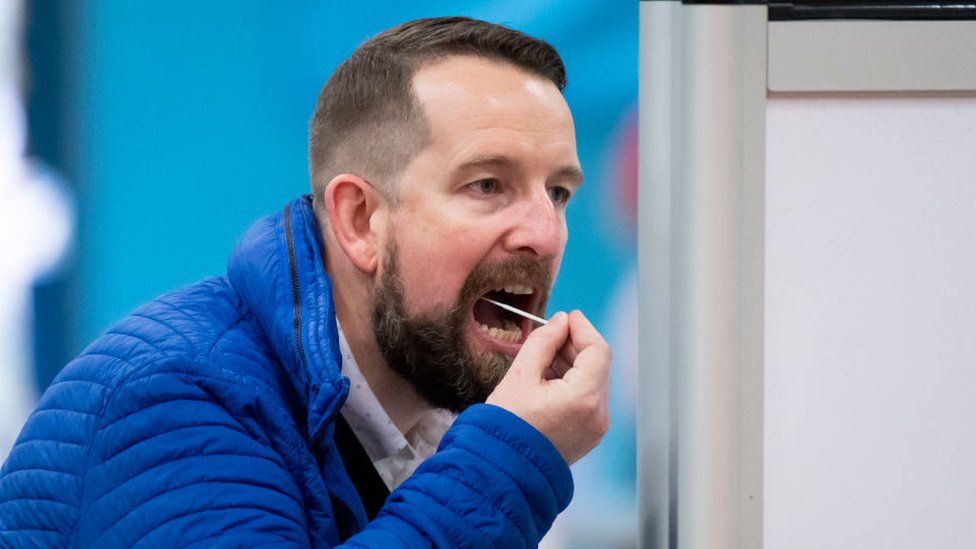 A man takes a lateral flow test using a swab at Merthyr Tydfil Leisure Centre