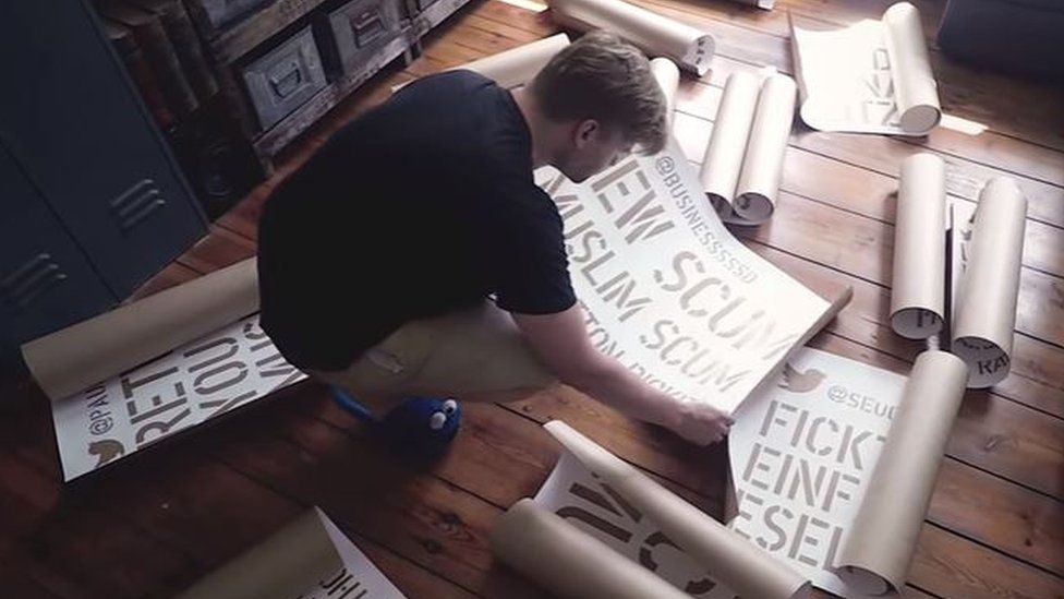 Shahak Shapira pictured in a screengrab from his YouTube video, with the stencils he made to spray-paint the offensive tweets