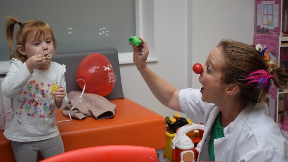 A Clown Doctor entertains a young patient