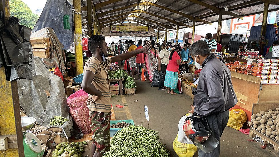 Sri Lankans walk on a deserted street at a wholesale market during