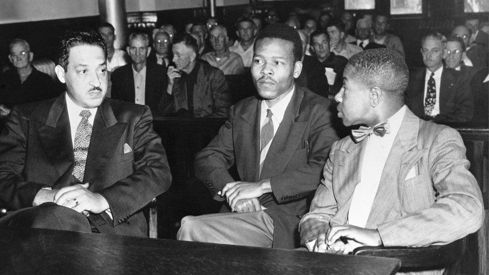 One of the pardoned men, Walter Irvin, speaks with his lawyers during his trial