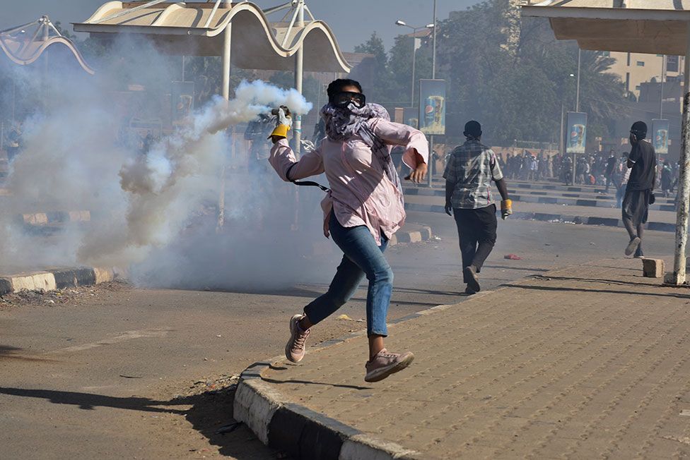 A protester throws back a tear-gas canister during a march demanding an end to military rule, in Khartoum, Sudan, on 30 December 2021