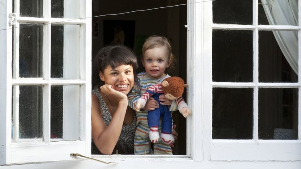 Woman and toddler looking out of an open window