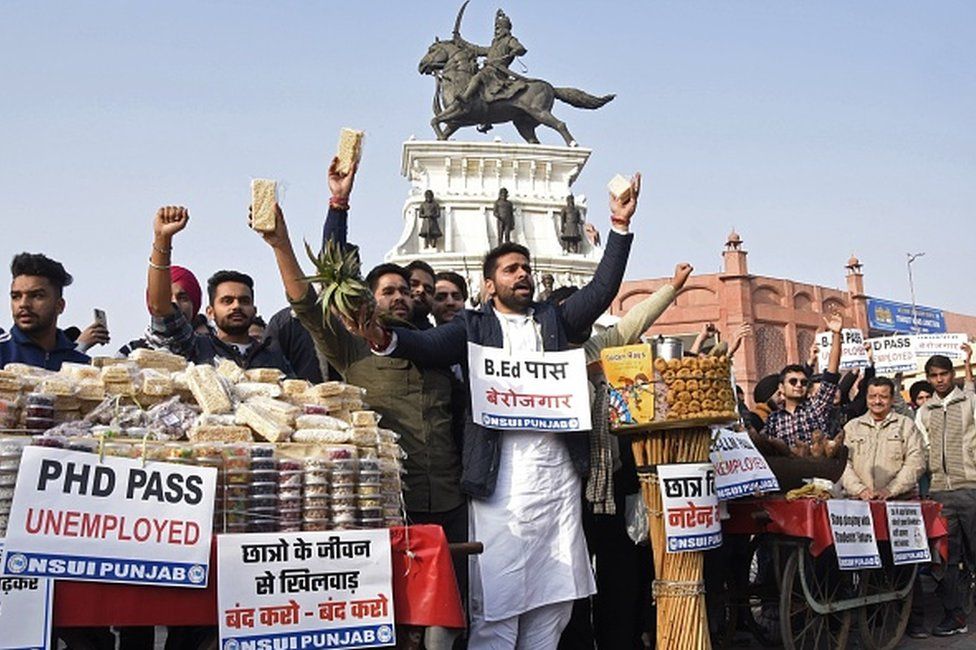 Activists of National Students' Union of India (NSUI) shout slogans against the central government as they enact to sell sweets and fruits during a protest against the rise of unemployment, in Amritsar on January 12, 2021.