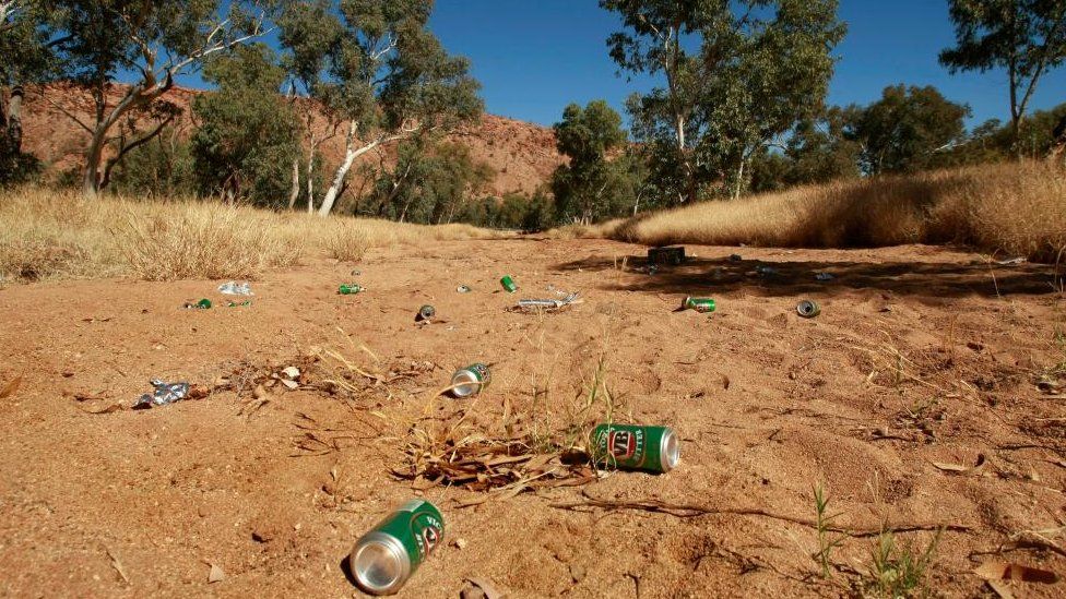 Beer cans lie on a dried up river bed in Alice Springs