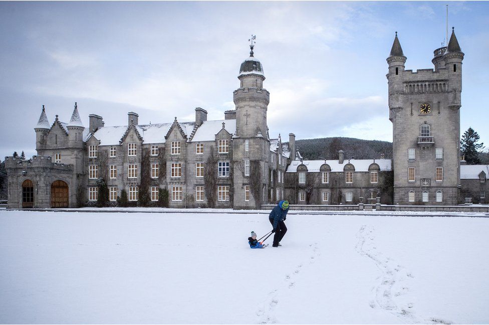 Geraint Stone pulls his two-year-old son Arthur on his sledge across the snow-covered lawn in front of Balmoral Castle, Royal Deeside