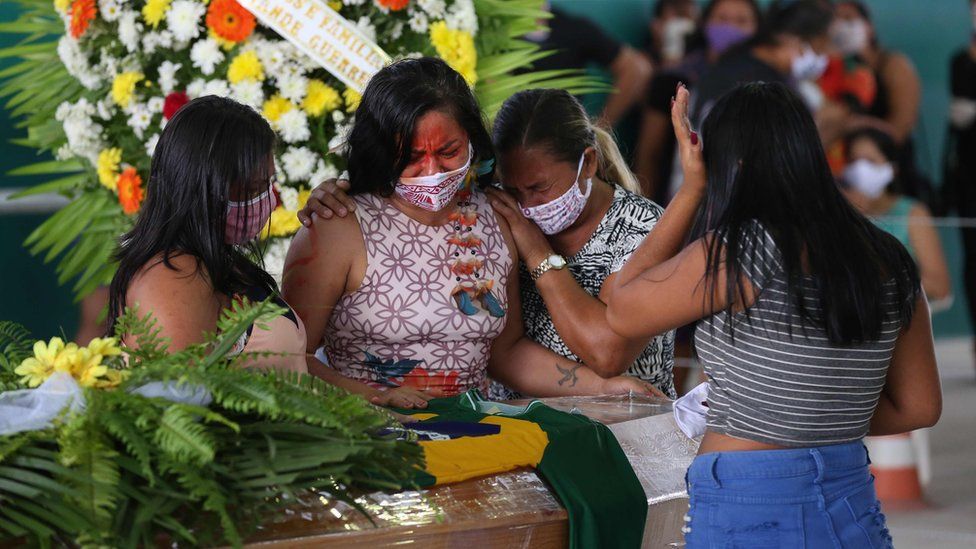 Indigenous from the Parque das Tribos community mourn besides the coffin of an indigenous leader