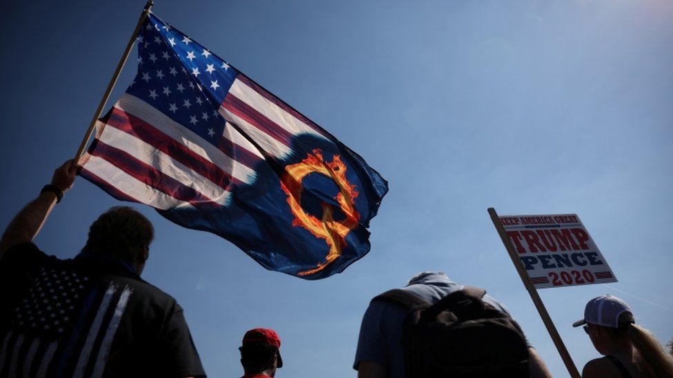A supporter of President Donald Trump holds an US flag with a reference to QAnon