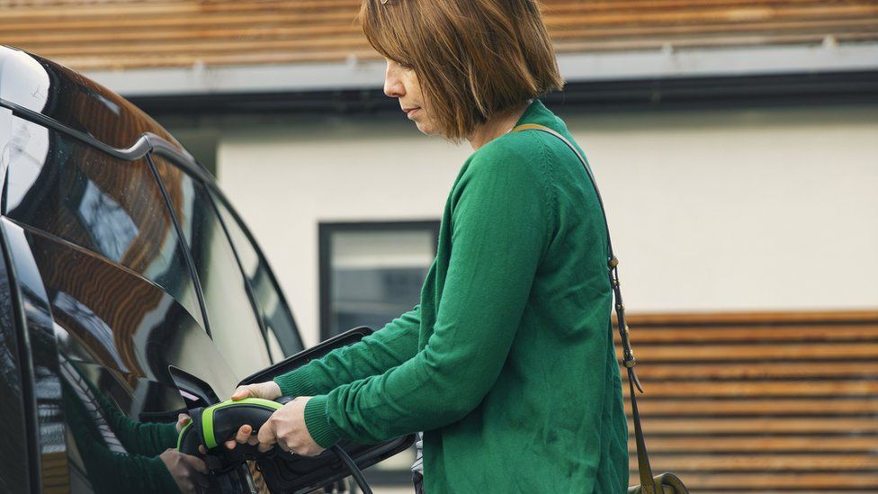 Woman plugging in electric car