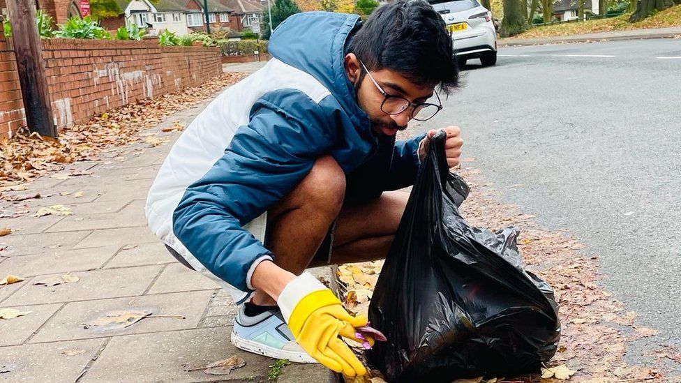 Vivek bending down on the side of the road and picking up litter