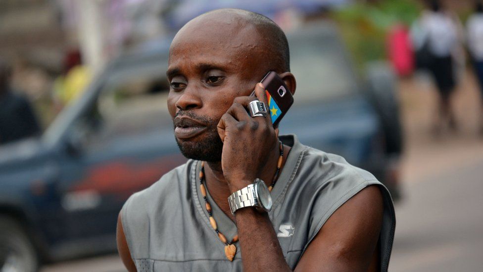 A man in Kinshasa holding a phone