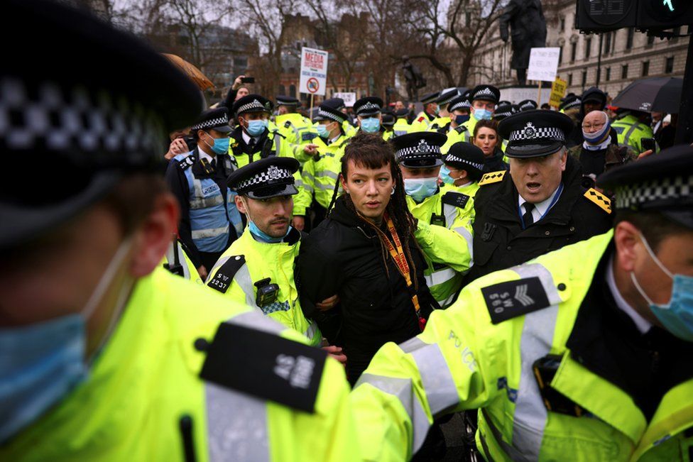Police officers detain an anti-vaccination activist during a demonstration in Parliament Square in London, 14 December 2020