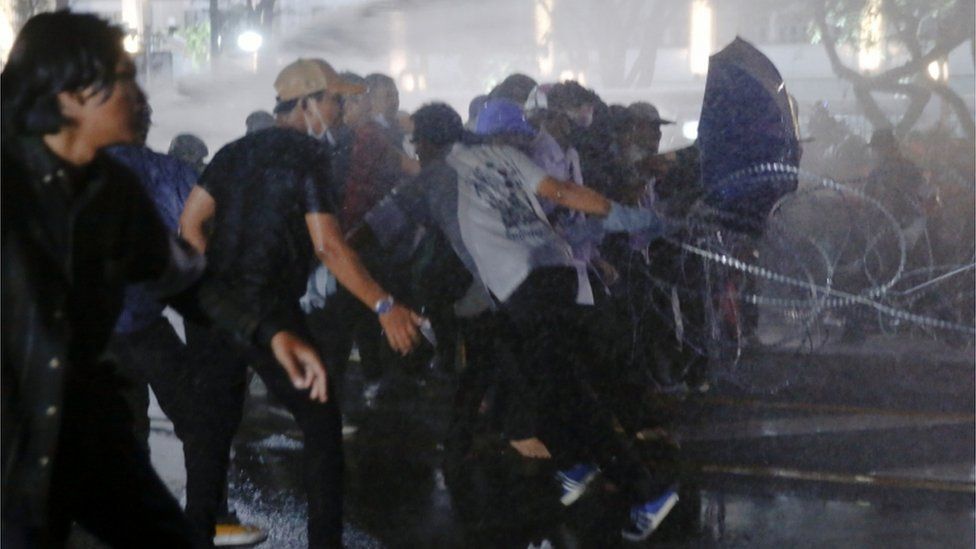 Protesters run as police use water cannon against them in Bangkok