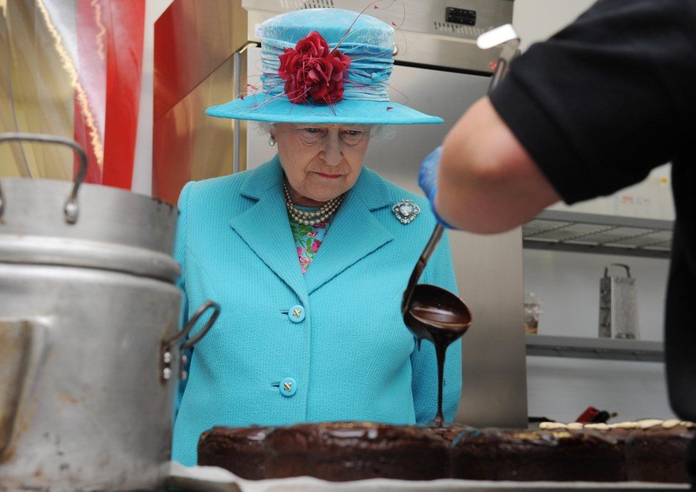 Queen Elizabeth II watches as a cook from the Pie Mill makes a chocolate cake at the Cumbrian Rural Enterprise Agency on 5 June, 2008 in Cumbria
