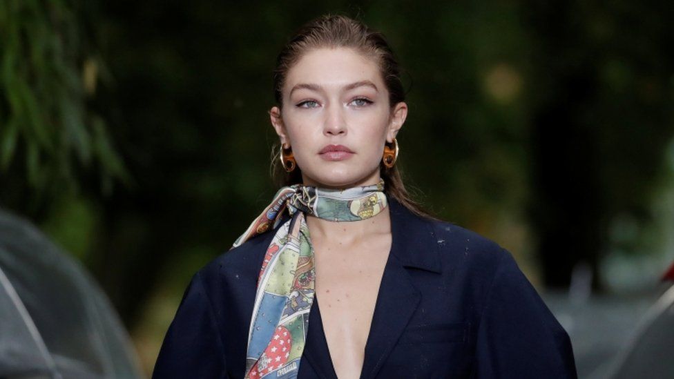 Gigi Hadid models in Paris wearing a large blue wool coat and a floral silk scarf