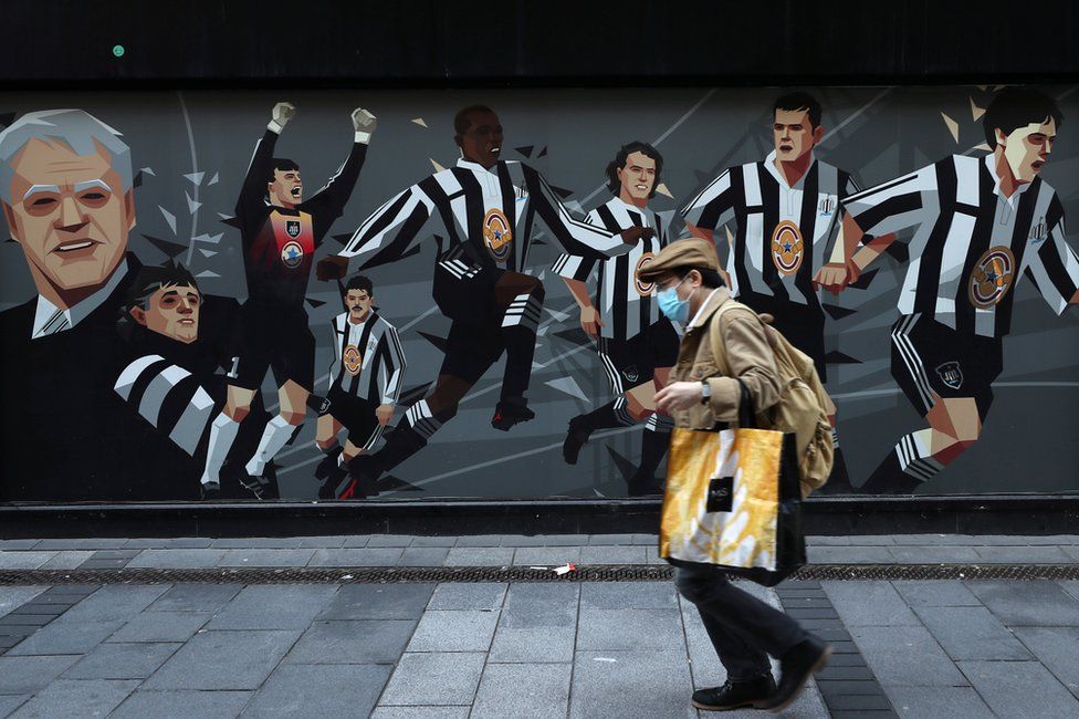 Man with mask walks past Newcastle United mural