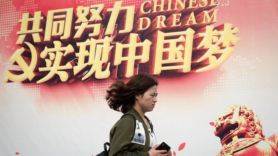 A woman walks past a billboard promoting the "Chinese Dream", a slogan associated with Chinese president Xi Jinping, in Beijing