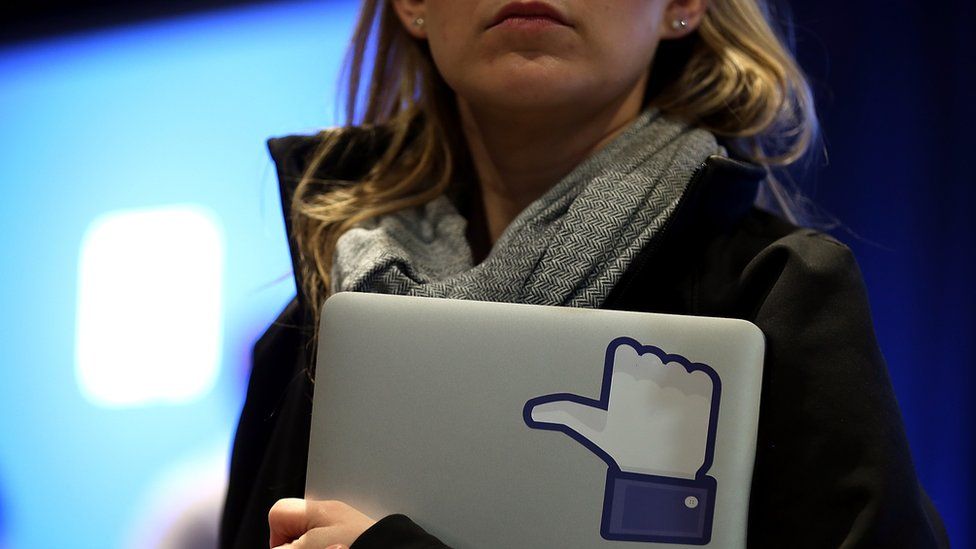 woman holding laptop with Facebook "thumbs up"
