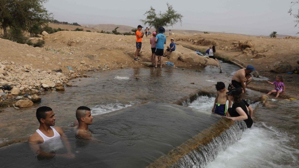 Palestinian youths and Jewish settlers gather at a water spot near the occupied West Bank village of al-Auja in the Jordan valley on 15 May 2020, as the region heads into a heat wave
