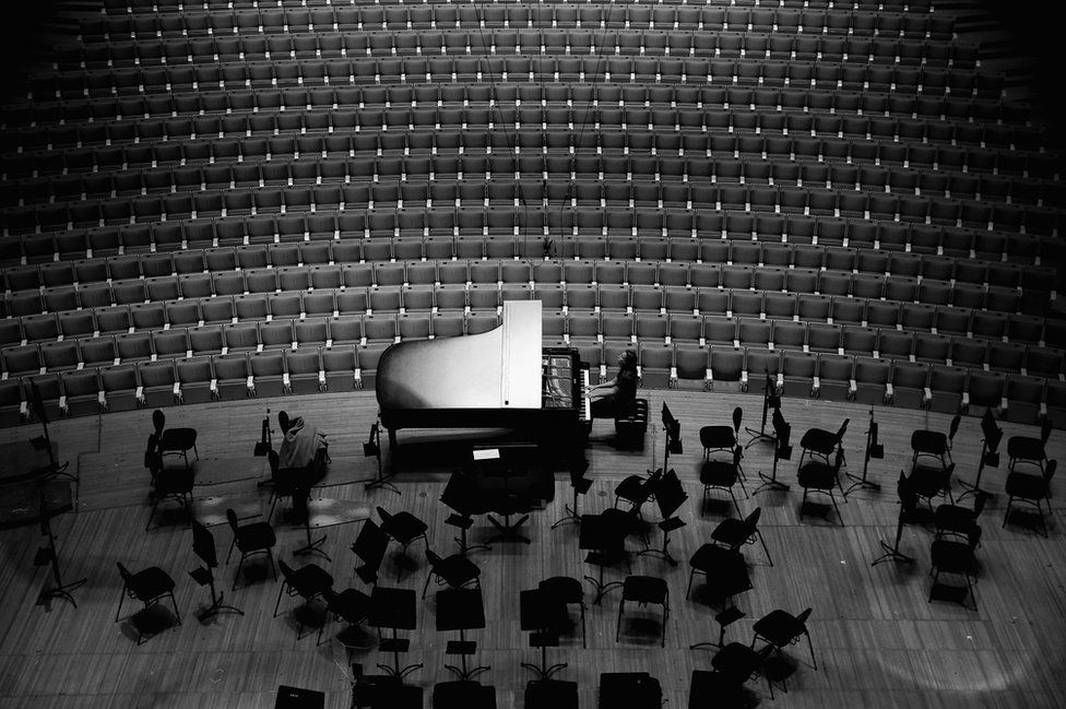 A pianist rehearses on a grand piano in the concert hall