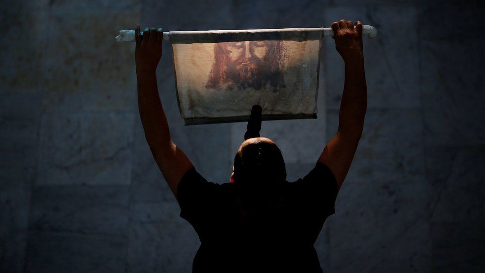 A woman holds a cloth with an image of Jesus Christ during the Good Friday at Brasilia Cathedral