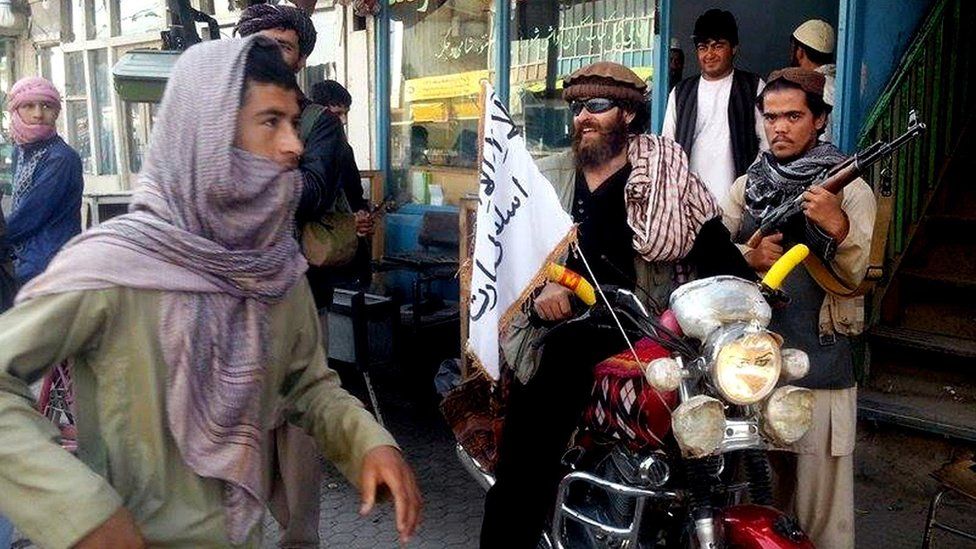 In this Sept. 29, 2015 file photo, a Taliban fighter sits on his motorcycle adorned with a Taliban flag on a street in Kunduz, Afghanistan