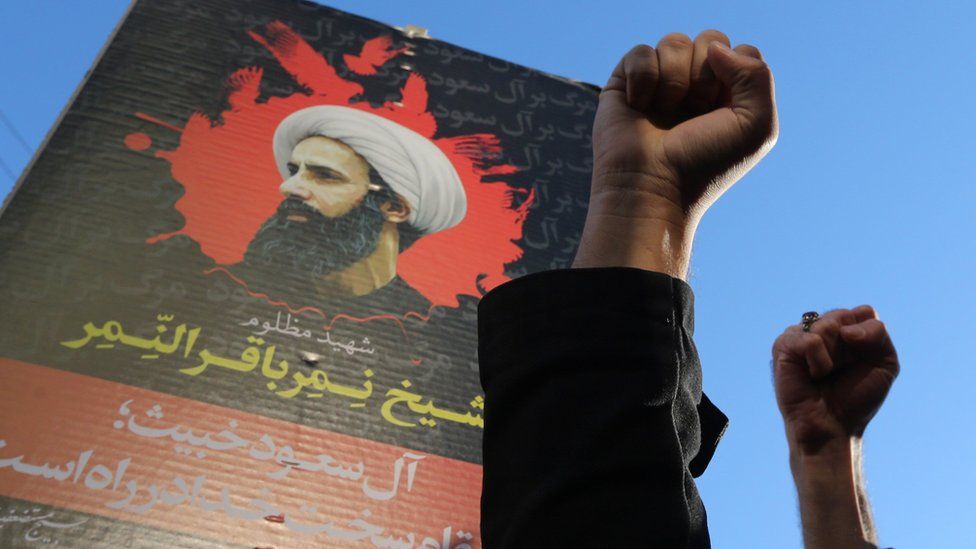 Iranian protesters raise their fists in front of a portrait of Saudi Shia cleric Nimr al-Nimr following execution (3 January 2016)