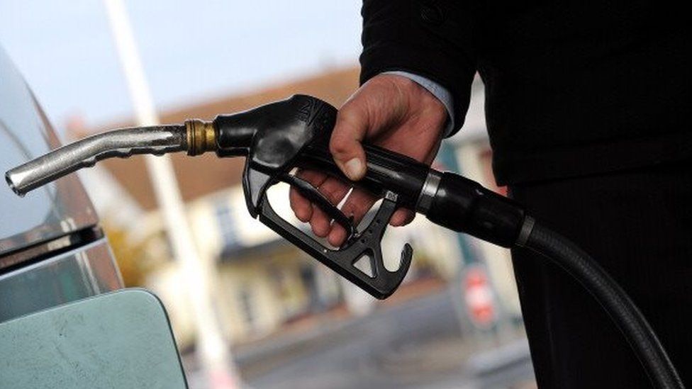 A customer pulls the nozzle of a petrol pump from their car at a petrol station in Egham