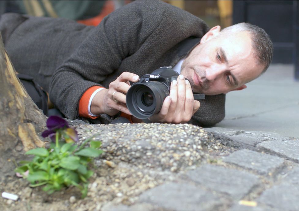 Paul Harfleet taking a photo of a pansy that he has planted