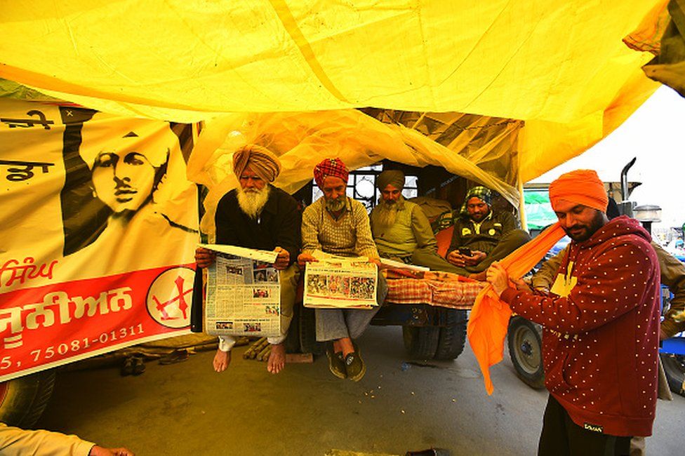 Демонстранты читают газету на участке протеста на границе Сингху (Дели-Харьяна) во время продолжающейся акции протеста против новых сельскохозяйственных законов 22 декабря 2020 года недалеко от Нью-Дели, Индия.