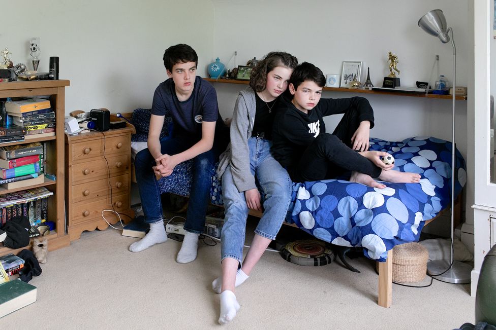 Three children sitting in a bedroom