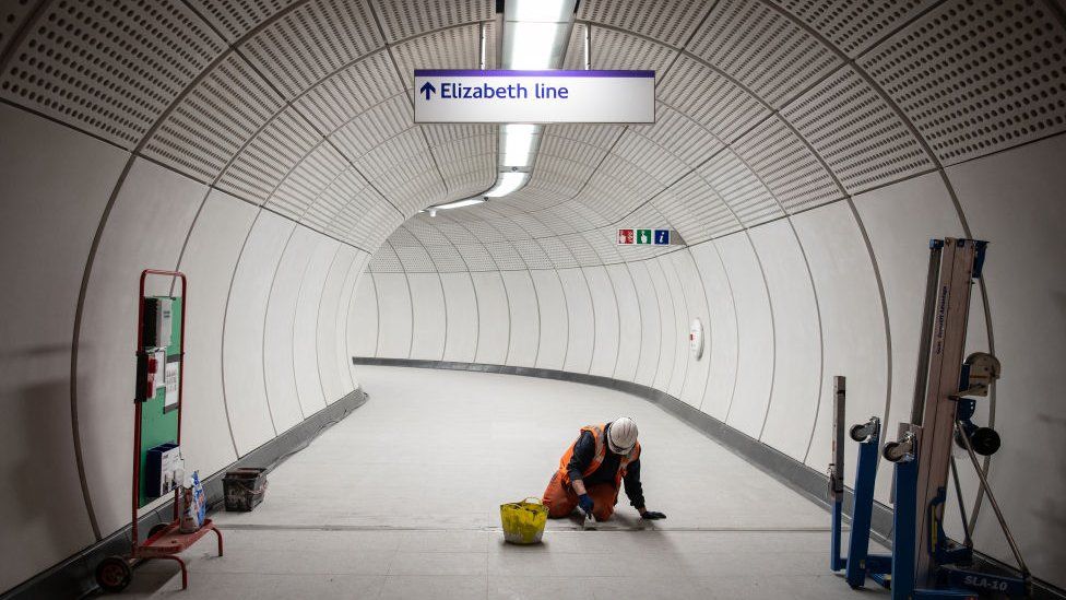 A member of the construction team works on the flooring in an access corridor within Liverpool Street Crossrail station