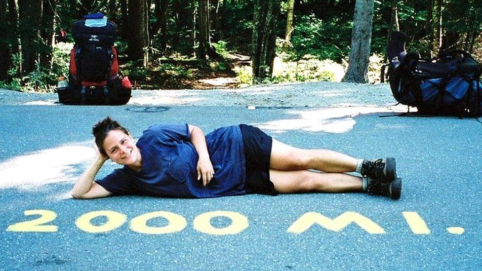 Woman beside a sign that reads 2000 miles