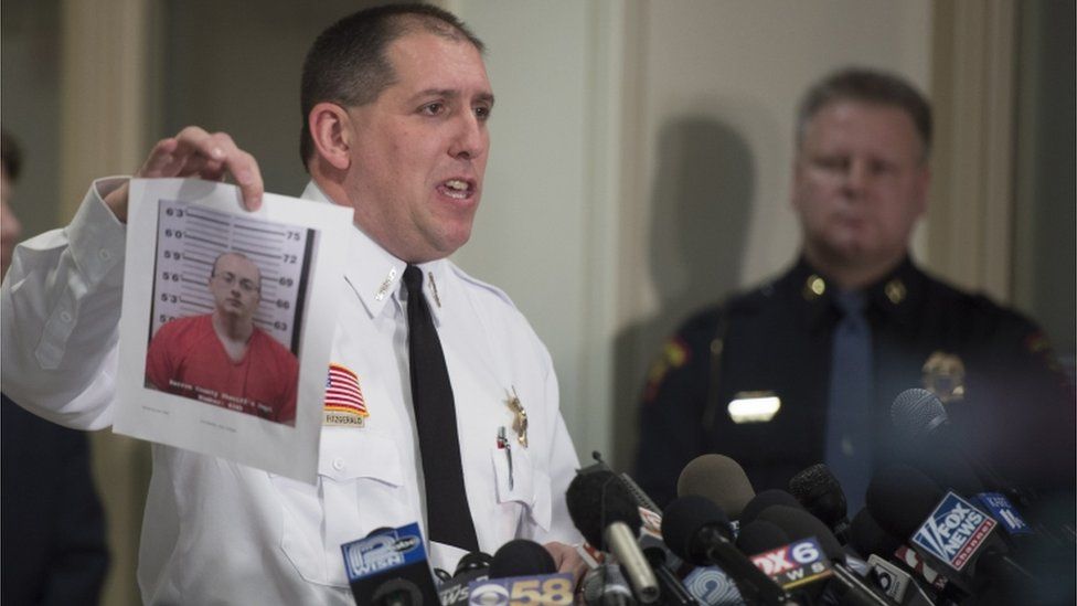 Baron County Sheriff Chris Fitzgerald holds up a photo of the suspect