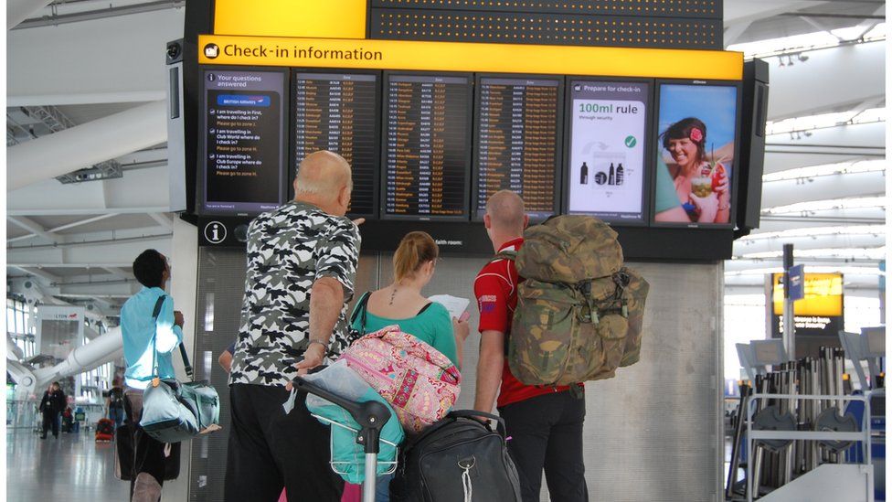 A family looks at a signboard in Heathrow Terminal 5