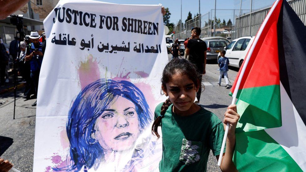 File photo showing a girl holding up a banner saying "Justice for Shireen" and a Palestinian flag as US President Joe Biden visits Augusta Victoria Hospital in East Jerusalem (15 July 2022)