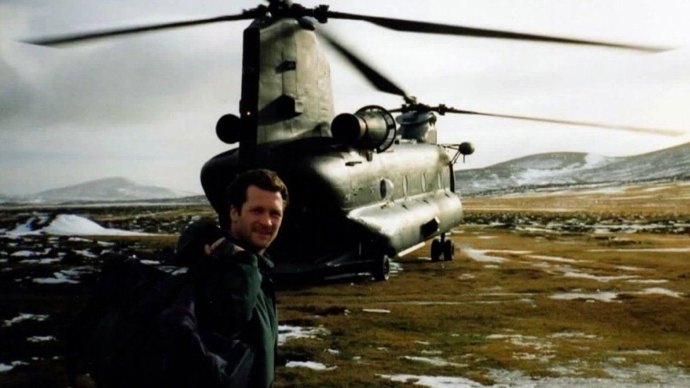 A man stands in front of a helicopter