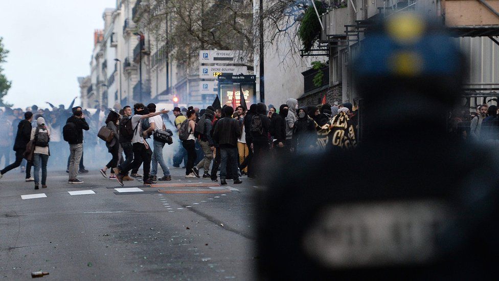 A riot policeman overlooks protesters in Nantes