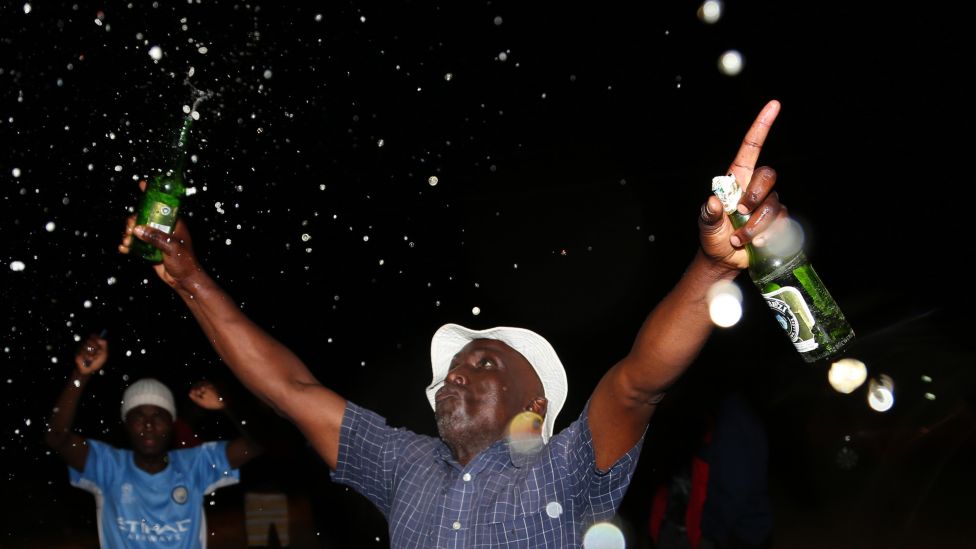People holding beer bottles celebrate the New Year in Ruwa, Zimbabwe - Saturday 1 January 2022