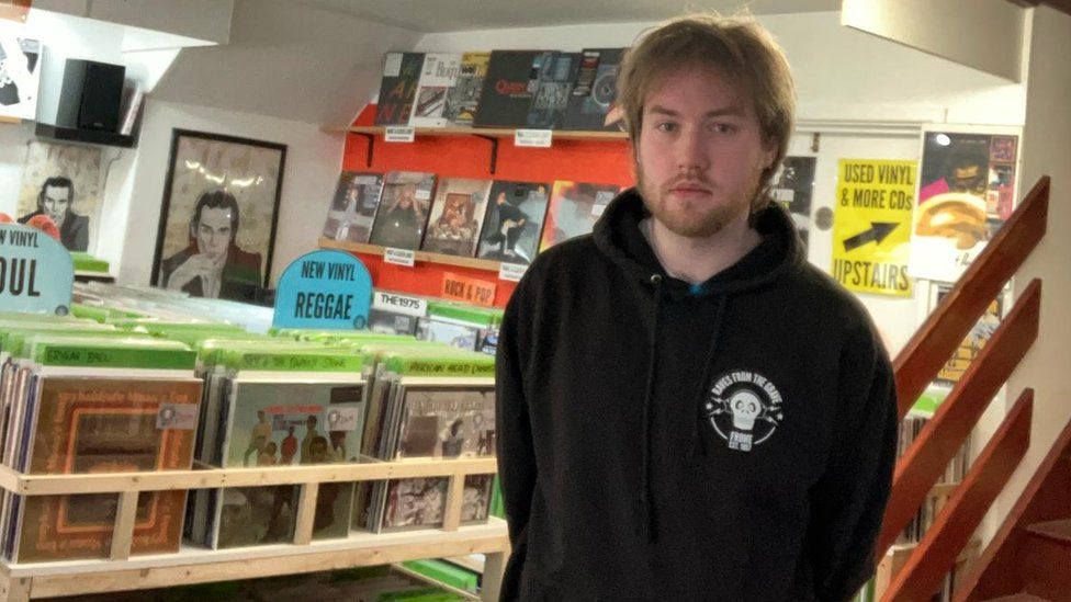 Jimmy Broklesby stood in front of a records shop in Frome in Somerset. There are various CDs and vinyl records, from different genre's including hip hop, reggae and soul.