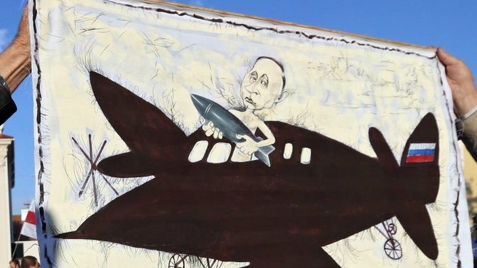 A placard depicting Russian President Vladimir Putin with a bomb on a plane is held by protesters in Minsk. Photo: 4 October 2015