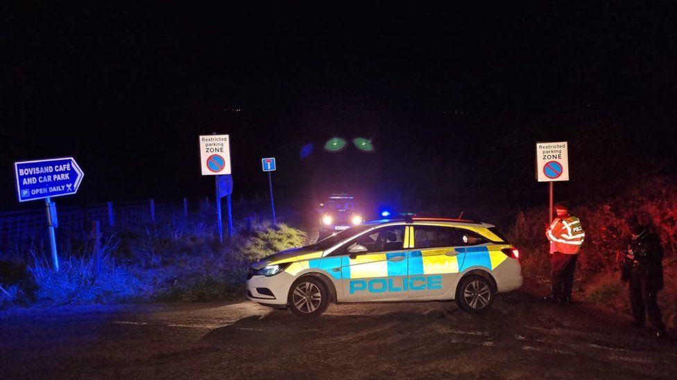 Police car blocking a road in the dark near Bovisand